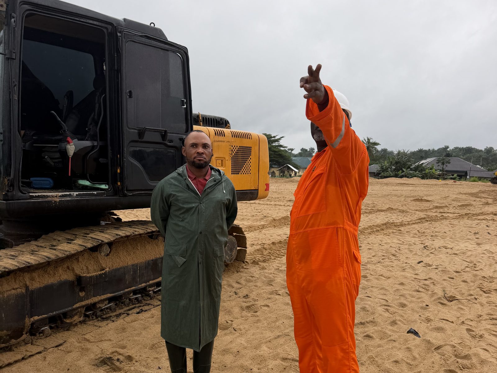 Site supervisor directing excavator work on the sand fill